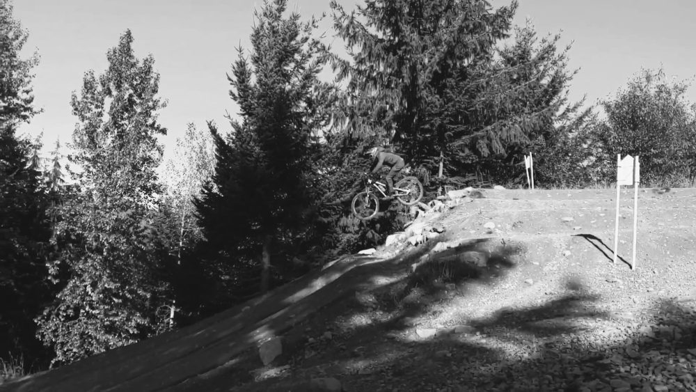 Black and white photo of a mountain biker in the air off a jump